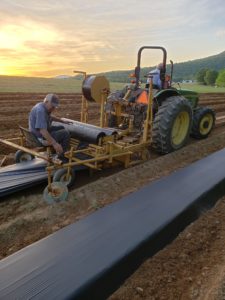Man on tractor with sunset in the distance.