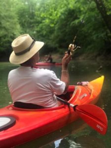 man fishing in canoe on river