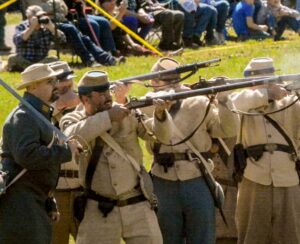 Reenactors in uniform firing muskets