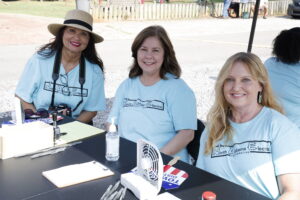 3 women engaged in conversation while seated around a table, sharing ideas and enjoying each other's company.