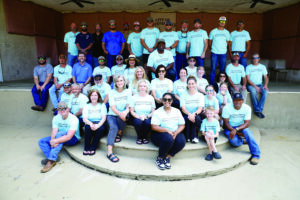 A diverse group of individuals in matching t-shirts smiling and posing together for a group photo.